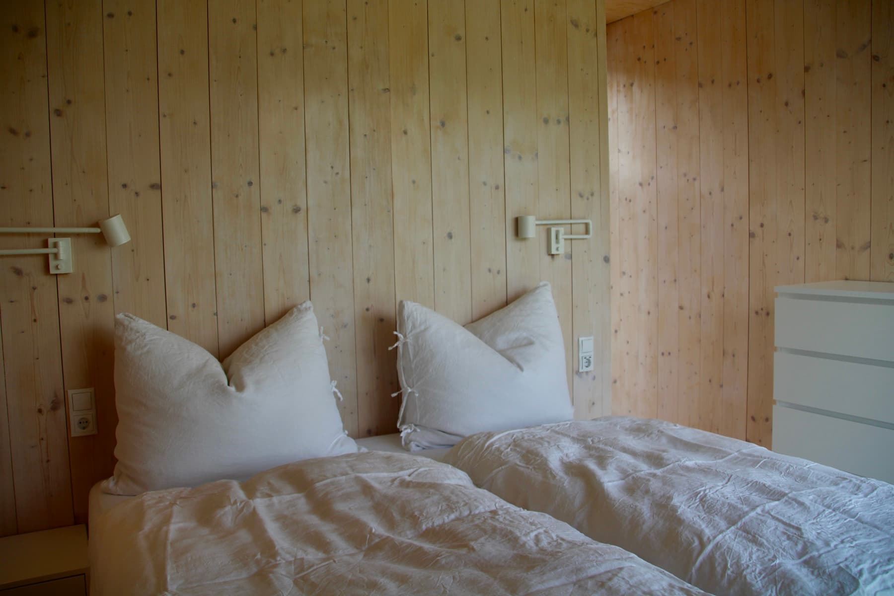 Schlafzimmer mit Holzwänden und Leselampen – Ferienwohnung Ramsau am Dachstein
